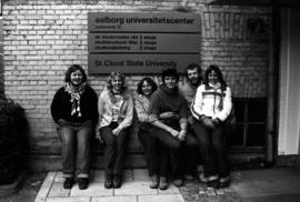 St. Cloud State students sit by a sign at Aalborg University Center