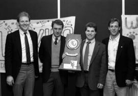 Craig Dahl, Herb Brooks, Bill Ries, and Bob Motzko stand together with the Division 3 third place hockey trophy, St. Cloud State University