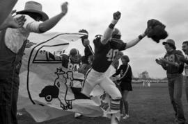 Football players run through a homecoming banner, St. Cloud State University