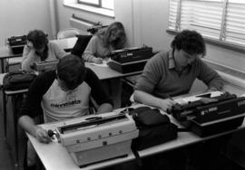 Men and women sit at tables with typewriters, St. Cloud State University