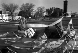 Homecoming queen Leslie Hansen and king Chuck LeMaire ride in a car during the homecoming parade, St. Cloud State University