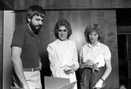 Joe Basil, Janet Leighton, and Michaela Meyer look at May Bowle event decorations, St. Cloud State University