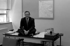 John Tomlinson sits on his desk, St. Cloud State University