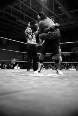 Wrestler Derrick Dukes has Pat Tanaka in a bear hug during a match at the Sauk Rapids High School