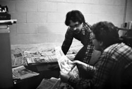 Two men look through newspapers, KVSC trivia weekend, St. Cloud State University