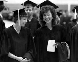 Two women talk to each other at commencement, St. Cloud State University