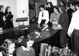 Students crowd together near the circulation desk, Old Model School (1906), St. Cloud State University