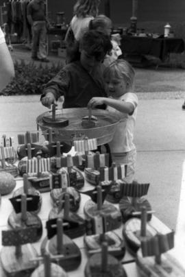 Two children float boats in a small barrel, Lemonade Concert and Art Fair, St. Cloud State University