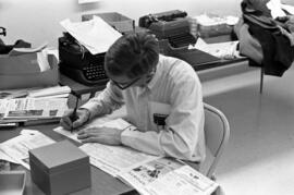 Man writes on copies of the Chronicle newspaper in the Chronicle newsroom, St. Cloud State University