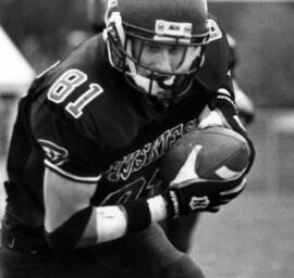 Mike McKinney runs with a football during a football game, St. Cloud State University