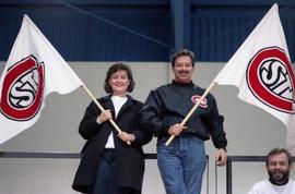 Sue and Bill Prout with flags during St. Cloud State University and Lake Superior State University men's hockey game