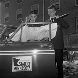 Two members of the men's tennis team takes a look at a map behind Lawrence Hall (1905), St. Cloud State University