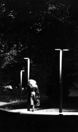 A woman walks on a sidewalk at night, St. Cloud State University