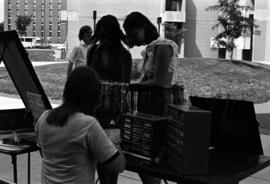 Two women examine merchandise on a table, Lemonade Concert and Art Fair, St. Cloud State University