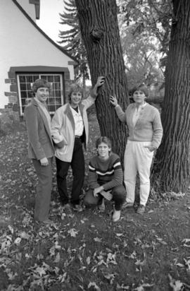 Women's basketball players Jill Gebeke, Dawn Anderson, Janice Flicker, and Carol Thelen stand in front of the Alumni House (1973), St. Cloud State University