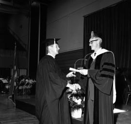 President George Budd gives a graduate his diploma during commencement, St. Cloud State University