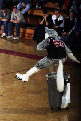 Blizzard the Husky mascot jumps over a garbage can during a men's basketball game, St. Cloud State University