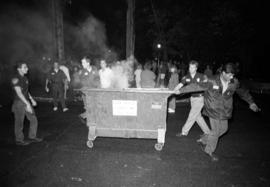 A Public Safety officer moves a dumpster on fire during the homecoming riots, St. Cloud State University