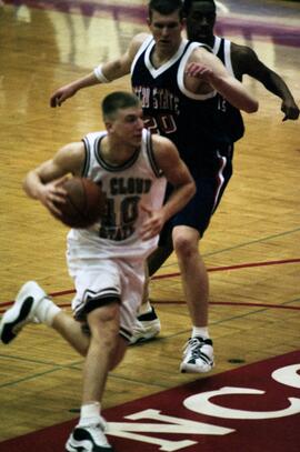 Jason Kron runs with a basketball during a basketball game, St. Cloud State University