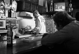 Flat Iron bartender Darrell Peterson cooks while customer Mark Fitzharris looks on, St. Cloud