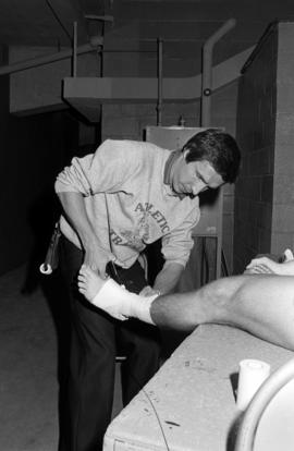 Athletic trainer Frank Zezoney wraps the leg of an athlete, St. Cloud State University