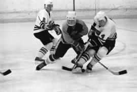 Three hockey players fight for the puck, St. Cloud State University