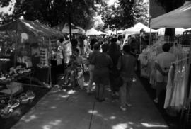 People walk on a sidewalk looking at vendors' booths, Lemonade Concert and Art Fair, St. Cloud State University