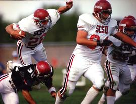 Football player runs with a football, St. Cloud State University