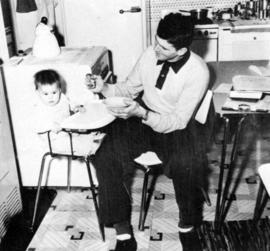 A man feeds a child at the Veteran's Housing (1946) complex, St. Cloud State University