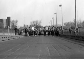 Marching band marches across a bridge during a homecoming parade, St. Cloud State University