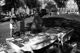 A woman arranges her merchandise on a table, Lemonade Concert and Art Fair, St. Cloud State University