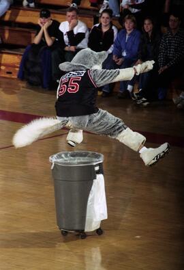 Blizzard the Husky mascot jumps over a garbage can during a men's basketball game, St. Cloud State University