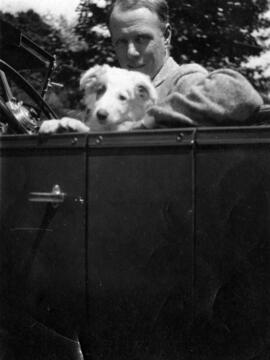 Sinclair Lewis sits in a car with a dog