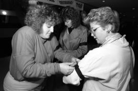 A woman puts on arm band on another woman to protest the violence of Homecoming weekend, St. Cloud State University