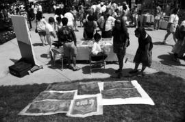 Women examine prints displayed on the lawn, Lemonade Concert and Art Fair, St. Cloud State University