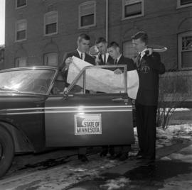 The men's tennis team takes a look at a map behind Lawrence Hall (1905), St. Cloud State University