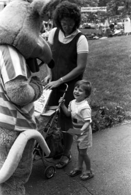 A mascot greets a child and mother, Lemonade Concert and Art Fair, St. Cloud State University