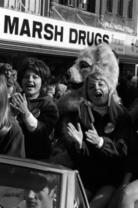 Women ride in a car during the homecoming parade in downtown St. Cloud with the Husky mascot, St. Cloud State University